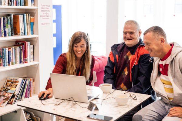People smiling looking at a laptop on a table