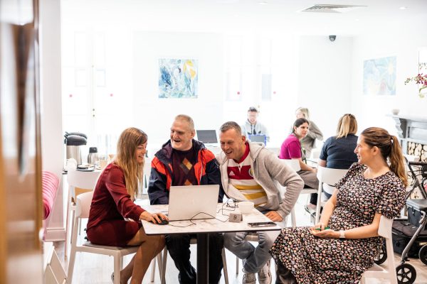 Customers sitting around a table smiling looking at a laptop